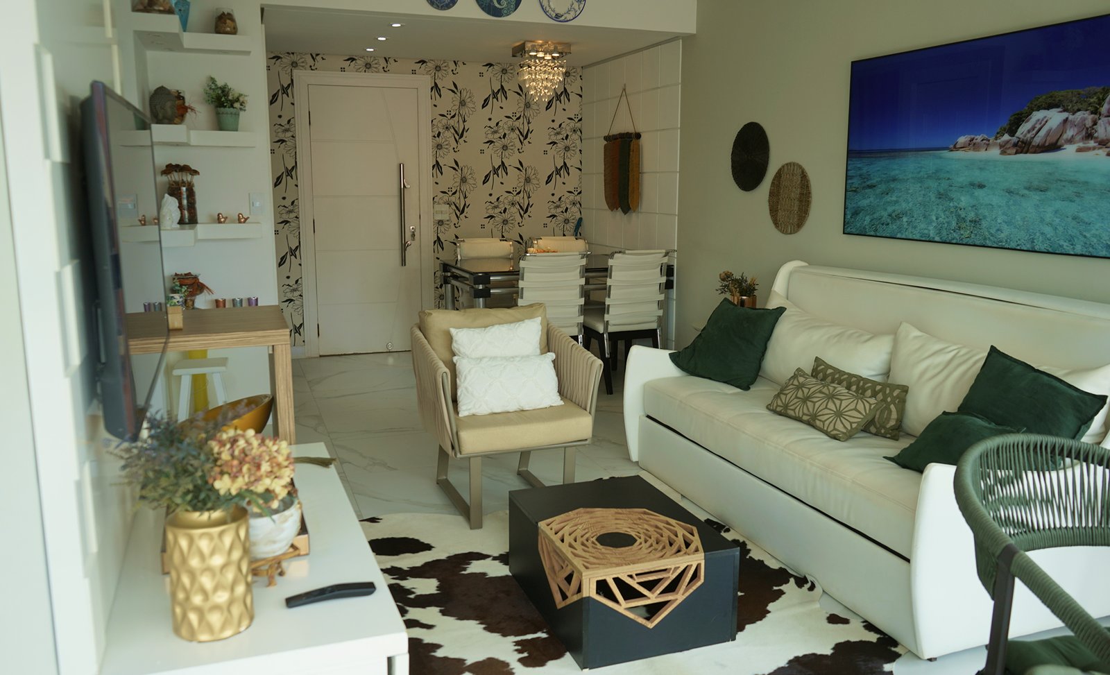 Sala de estar integrada à sala de jantar em apartamento decorado, com sofá branco, poltronas, mesa de centro moderna